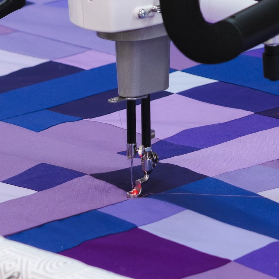 Quilting machine with a digital display on a quilt with a geometric pattern.