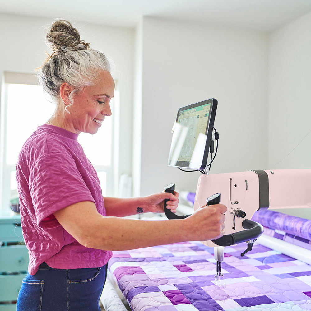 Woman operating a longarm with a digital display in a home setting